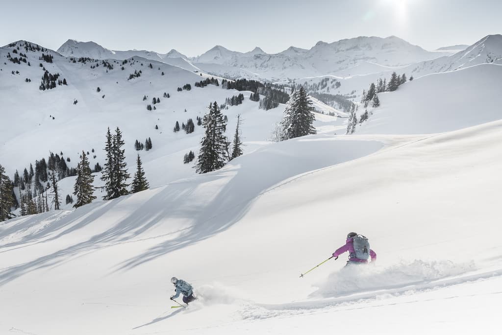 Skiiers skiing down fresh snow slope