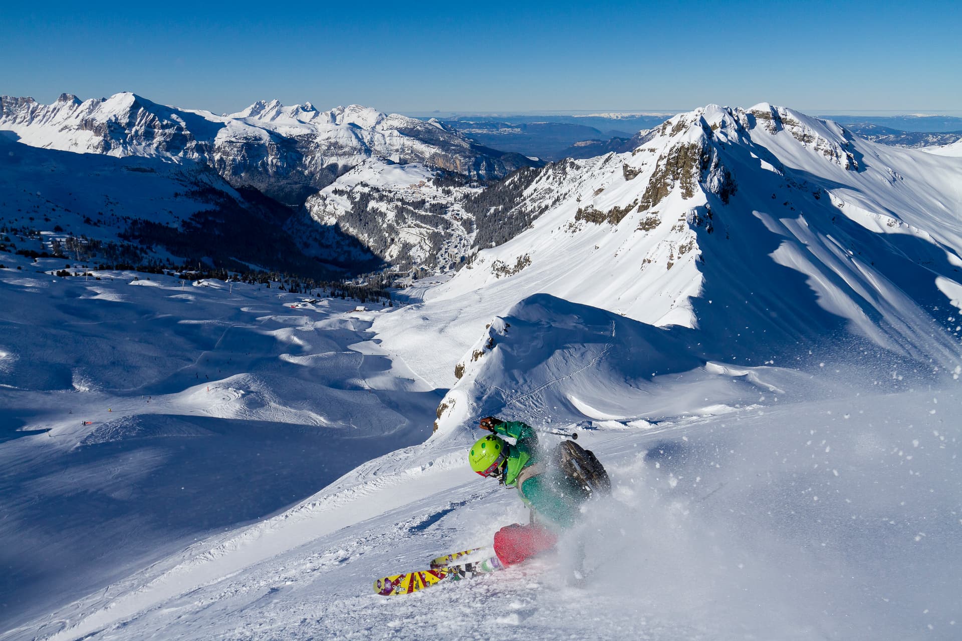 Skiier carving turn down ski slope with French Alps in background